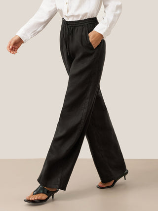 Charcoal black 100% linen classic pants from LINTICO, featuring a relaxed fit and tailored waistband on a model.