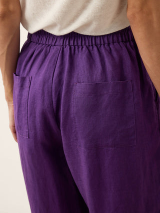 Dark purple linen tapered pants with artisan button details from LINTICO's Katherine collection, showcasing relaxed, tapered fit.