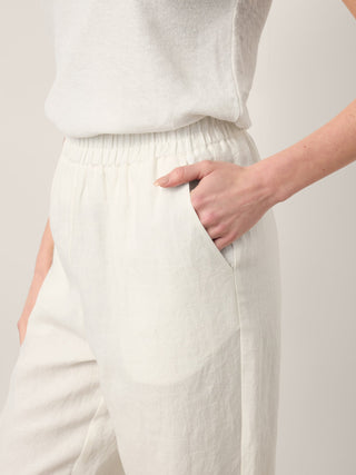 LINTICO Lindsey 100% linen double pleat pull-on pants with button hem in optic white, featuring a relaxed fit and comfortable waistband.