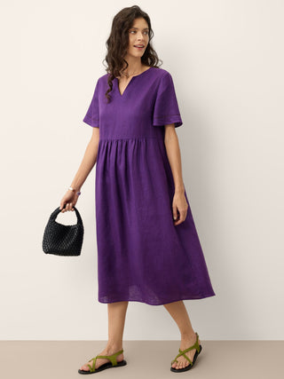 Dark purple linen maxi dress by LINTICO with embroidered cuffs and split neck, featuring a flowing silhouette and elegant design.