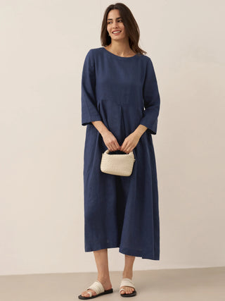 LINTICO linen maxi dress with bateau neckline and pleated design, showcasing a flowing, elegant silhouette in natural fabric.
