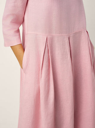 LINTICO linen maxi dress with crescent neckline, decorative buttons, and waist pleats, featuring a flowing, elegant design.