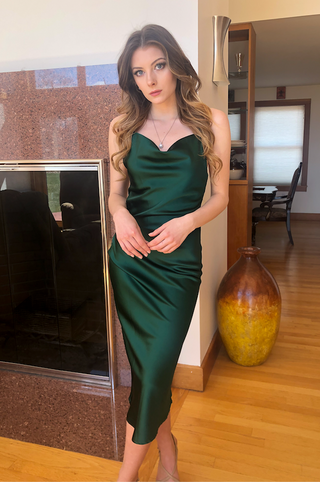 Emerald green satin Aspen midi dress by Lady Black Tie, displayed on a hanger with a fitted slip design and elegant fabric texture.