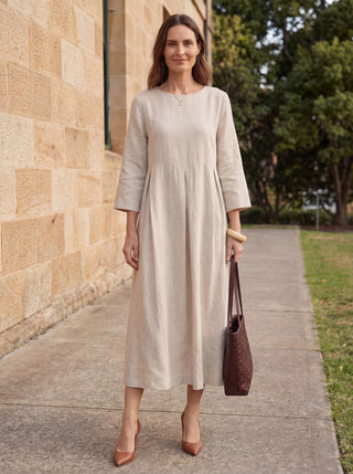 Natural linen maxi dress with bateau neckline and pleated design by LINTICO, showcasing a flowing, elegant silhouette.