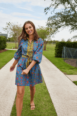 Halle Collared Belted Mini Dress in Blue Floral with long sleeves and yellow floral trim, styled outdoors with sandals.