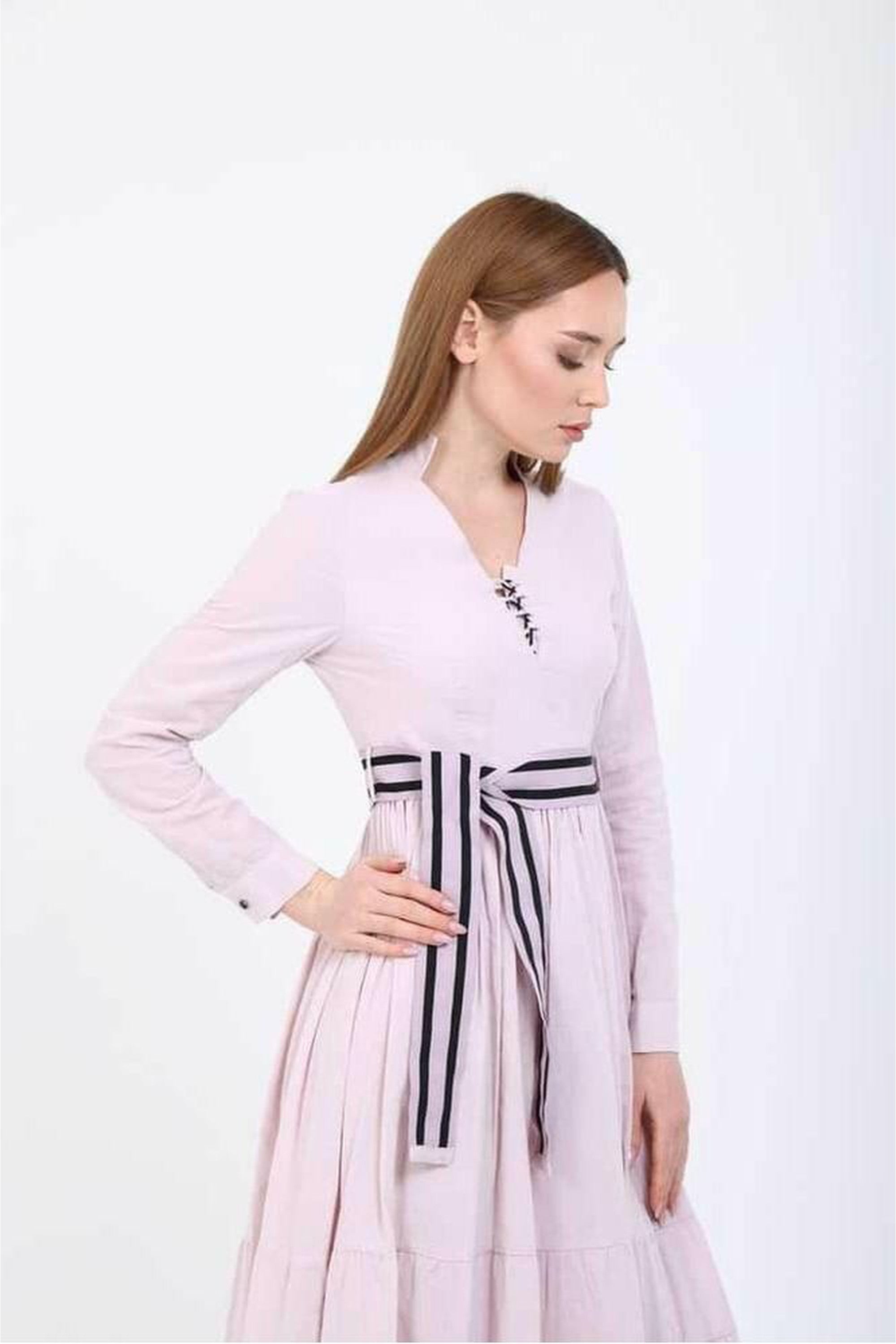 BY Baano Elise V-neckline midi dress in summer fabric with a belt, displayed on a hanger with a floral background.
