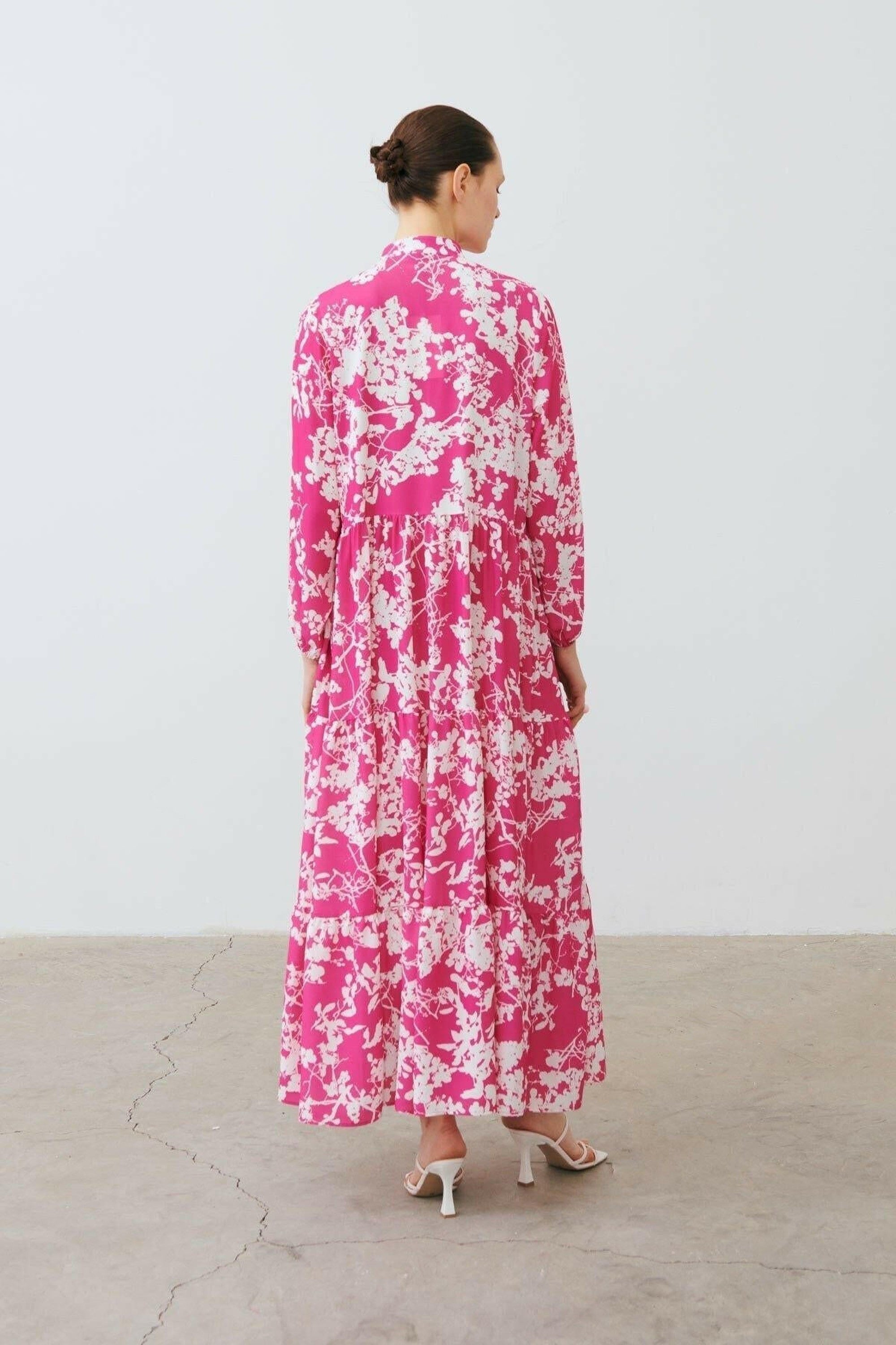 Light pink Polly Floral Maxi Dress by By Baano, featuring a flowing silhouette and floral pattern, perfect for elegant occasions.