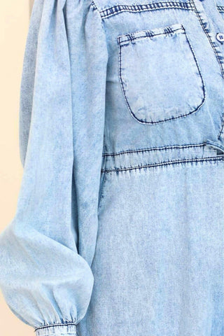 Light wash midi denim dress by By Baano featuring a fitted bodice and flared skirt, styled with pockets and shoulder straps.